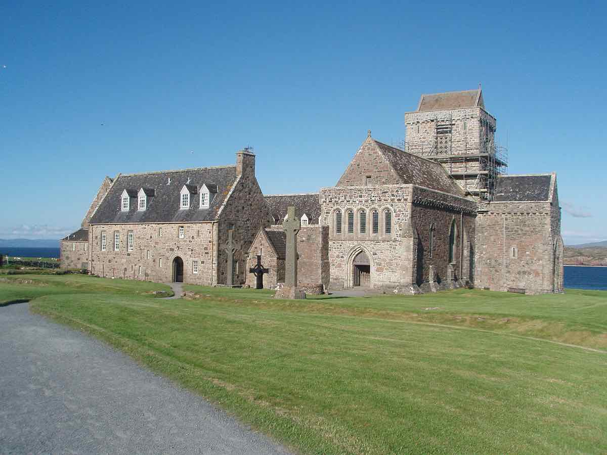 L'abbazia di Iona: un'abbazia di pietra grigia con una torre quadrata, su un prato vicino al mare