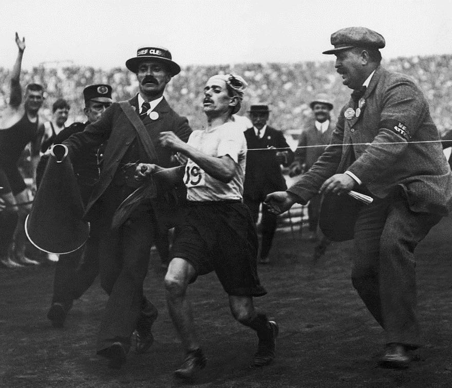 L'arrivo della maratona alle Olimpiadi di Londra del 1908: il corridore italiano Dorando Pietri, sul punto di crollare, viene aiutato dai giudici a tagliare il traguardo